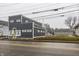 Modern commercial building with gray siding and yellow door on a street with other buildings at 2329 Shelby St, Indianapolis, IN 46203
