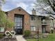 Inviting condo exterior featuring a brick facade, balcony, and lush landscaping at 4311 Village Parkway W Cir # 6, Indianapolis, IN 46254