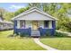 Charming bungalow with a covered front porch, yellow door, and landscaped front yard at 5817 Beechwood Ave, Indianapolis, IN 46219