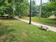 A view of a peaceful park featuring a well-maintained lawn, mature trees, a stone bench, and a walking path at 5817 Beechwood Ave, Indianapolis, IN 46219