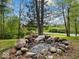 Stone fire pit surrounded by trees, creating a cozy outdoor gathering spot at 6827 S 500 W, Trafalgar, IN 46181