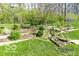 Backyard featuring terraced gardens, lush lawn, mature landscaping, small pond, and perimeter fence at 701 Danver Ln, Beech Grove, IN 46107