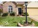 Inviting home with a manicured lawn, complemented by a two-car garage and an array of potted plants at 701 Danver Ln, Beech Grove, IN 46107