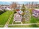 Aerial view of a cozy home with a green lawn, mature trees, and surrounding neighborhood at 702 S Fanning St, Sheridan, IN 46069
