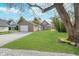 Well-manicured front yard with lush green grass, gravel driveway, mature trees, and a detached garage at 702 S Fanning St, Sheridan, IN 46069