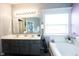 Well-lit bathroom with double sinks, soaking tub, decorative plants, and large mirror at 8748 N Autumnview Dr, McCordsville, IN 46055