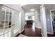 Hallway with wood floors, glass-paned doors, and a view into the living room and office space at 8748 N Autumnview Dr, McCordsville, IN 46055