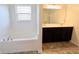 Bright bathroom with a large window, soaking tub and double vanity with dark cabinets at 9207 Foudray N Cir, Avon, IN 46123