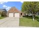 Charming brick home featuring a two-car garage, manicured lawn and mature shade tree at 9526 Colony Pointe E Dr, Indianapolis, IN 46250