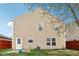 Back exterior view of home with tan siding, simple backyard, and greenery at 10881 August Dr, Ingalls, IN 46048