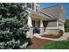 Charming front porch with brick pillars, two chairs, and colorful potted plants creating a welcoming entrance at 11014 Woodpark Dr, Noblesville, IN 46060
