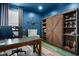 Stylish home office featuring blue walls, a large desk, and a custom sliding-door cabinet with trophy display at 11014 Woodpark Dr, Noblesville, IN 46060