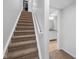 Carpeted staircase leading to a bathroom, featuring a white handrail and neutral decor at 11014 Woodpark Dr, Noblesville, IN 46060