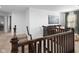 Well-lit upstairs landing with dark wood railing, plush carpeting, and a cozy seating area at 11014 Woodpark Dr, Noblesville, IN 46060