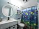 Well-lit bathroom featuring a vanity, round mirror, and a shower with a colorful fish-themed curtain at 1123 Barley Cir, Carmel, IN 46032