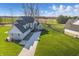 Aerial view showcases a grand, light-colored home with long driveway and large, green lawn next to a lake at 12536 Lowery Way, Fishers, IN 46037