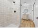 Modern bathroom features a tiled shower, wood floors, vanity and round mirror at 12536 Lowery Way, Fishers, IN 46037
