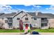 The exterior of a condominium building with a red door, balcony, brick accents, and lush lawn at 12588 Tennyson Ln # 205, Carmel, IN 46032