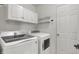 Well-lit laundry room with white washer, dryer, storage cabinets, and shelves at 1330 Redwood Dr, Greenfield, IN 46140