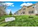 Large backyard with mature trees, green grass, and a paver patio with a stone firepit and seating area at 13314 Lansbury Ln, Fishers, IN 46037