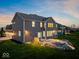 This home boasts a backyard with a stone patio, a built-in fire pit, and exterior lighting at 13314 Lansbury Ln, Fishers, IN 46037