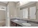 Modern bathroom featuring double sinks, large mirror, and granite counters and brown cabinetry at 13314 Lansbury Ln, Fishers, IN 46037