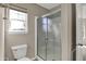 Bathroom featuring glass-doored shower and toilet adjacent to a window at 13314 Lansbury Ln, Fishers, IN 46037
