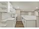 Bright kitchenette featuring white cabinetry, open shelving, bar top, and modern stainless steel dishwasher at 13314 Lansbury Ln, Fishers, IN 46037