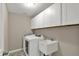Laundry room with front load washer and sink and white cabinets for storage at 13314 Lansbury Ln, Fishers, IN 46037