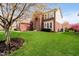 View of home with large yard, brick facade, and mature trees at 13933 Wildcat Dr, Carmel, IN 46033