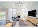 Bright living room with large windows, fireplace, modern ceiling fan, and comfortable gray sectional at 13933 Wildcat Dr, Carmel, IN 46033
