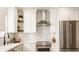 This modern kitchen showcases stainless steel appliances, white subway tile, and floating wood shelves at 15037 Rutherford Dr, Westfield, IN 46074