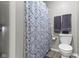 Well-lit bathroom featuring a patterned shower curtain, gray towels, toilet, and handrail at 1520 Norfolk Dr, Zionsville, IN 46077