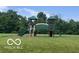 Neighborhood playground with climbing structure, slides, and swings on a green lawn surrounded by mature trees at 15723 Myland Dr, Noblesville, IN 46062