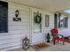 Charming porch features a wreath, red chair, lantern, and a 'Hello' door mat at 1629 N K St, Elwood, IN 46036