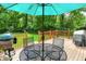 Outdoor back deck with dining set, umbrella, grill, and view of trees at 1697 Stacy Lynn Dr, Indianapolis, IN 46231