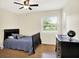 Cozy bedroom with hardwood floors, ceiling fan, large window, and a black wood dresser at 1697 Stacy Lynn Dr, Indianapolis, IN 46231
