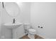 Modern half bathroom with pedestal sink, round mirror and sleek black fixtures at 2252 Marjorie Way, Shelbyville, IN 46176