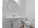 Modern powder room featuring a pedestal sink, round mirror, and neutral color palette at 2268 Marjorie Way, Shelbyville, IN 46176