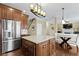 Open kitchen with a stainless steel refrigerator, granite counters, an island, and modern chandelier lighting at 300 Wyndotte Dr, Carmel, IN 46032