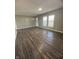 An empty living room ready for its new occupants offers hardwood flooring and two windows for light at 3642 Horth Ct, Indianapolis, IN 46235
