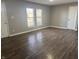 An empty living room ready for its new occupants offers hardwood flooring and two windows for light at 3642 Horth Ct, Indianapolis, IN 46235