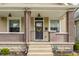 Inviting covered front porch with brick pillars, black railing and a wreath on the front door at 420 Orange St, Indianapolis, IN 46225