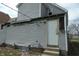 View of home exterior with gray siding, white door, and unfinished trim work at 425 N Grant Ave, Indianapolis, IN 46201