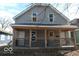Charming exterior of a two-story home featuring a cozy porch with wooden railings and gray siding at 425 N Grant Ave, Indianapolis, IN 46201