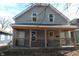 Two-story gray home with a covered front porch with decorative wood detailing and two front doors at 425 N Grant Ave, Indianapolis, IN 46201