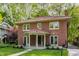 Beautiful two-story brick home featuring a unique red tile roof, inviting front porch, and lovely yard at 4343 N Pennsylvania St, Indianapolis, IN 46205