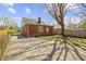 View of a brick home's backyard with a driveway, landscaping, and a wooden fence at 4640 Boulevard Pl, Indianapolis, IN 46208