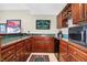 This bar area with wooden cabinets and green countertops includes a sink and mini refrigerator at 4843 Snowberry Bay Ct, Carmel, IN 46033