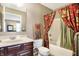A decorated full bathroom features a vanity sink, floral curtains, and neutral colored walls at 4843 Snowberry Bay Ct, Carmel, IN 46033